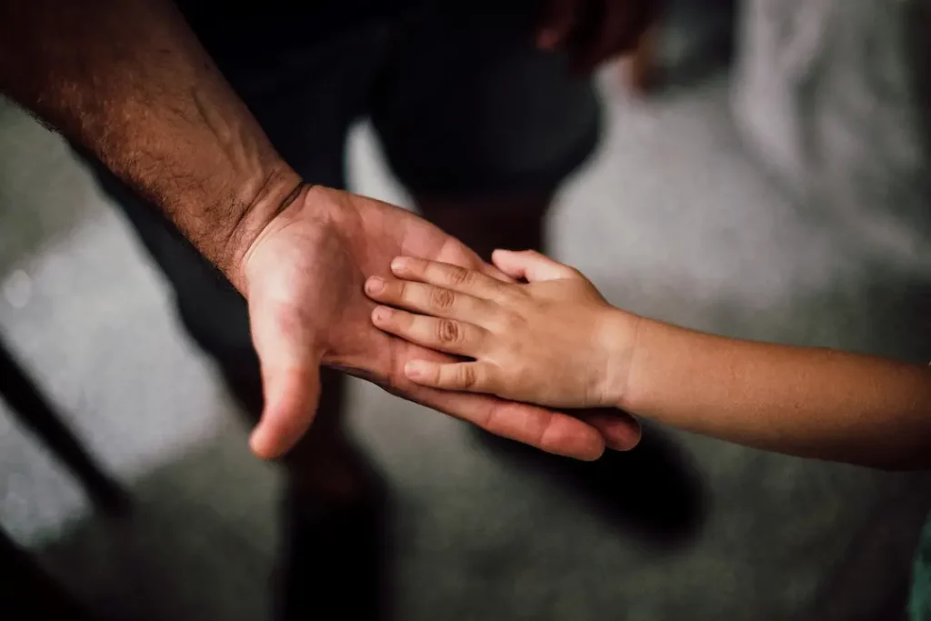 Picture of a parent holding hands with their child for the article about NC child support laws.