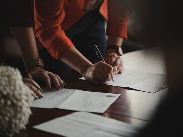 Picture of a couple signing a marriage prenup for the blog about what to include in a prenup agreement.